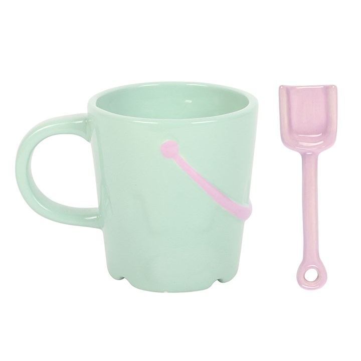 Mint green bucket-shaped ceramic mug with a matching lilac spade spoon beside it on a white background