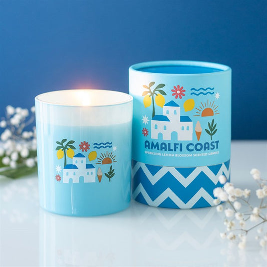 Sky blue frosted glass candle featuring white villa and lemon illustrations, sitting next to a matching blue and white chevron gift tube