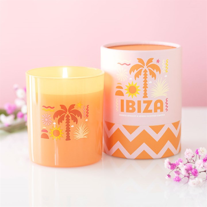 Orange frosted glass candle with Ibiza palm tree illustrations next to a matching orange and pink gift tube.