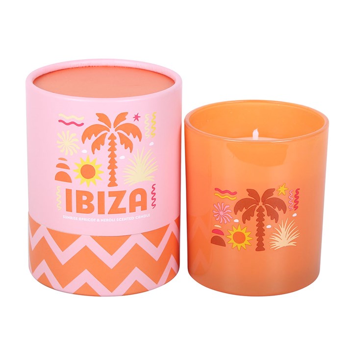 Orange frosted glass candle with Ibiza palm tree illustrations next to a matching orange and pink gift tube on a white background.