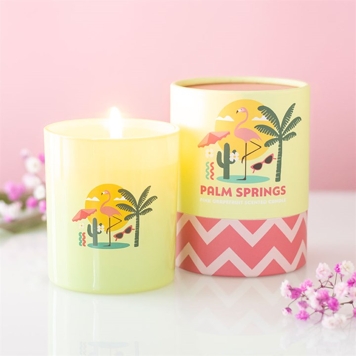Lime green frosted glass candle with pink flamingo and palm tree illustrations, sitting next to a matching green and pink gift tube.