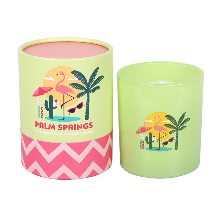 Lime green frosted glass candle with pink flamingo and palm tree illustrations, sitting next to a matching yellow and pink gift tube on a white background
