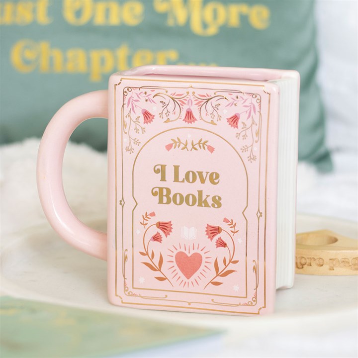 Pastel pink rectangular ceramic mug shaped like a hardcover book with gold floral illustrations and the words 'I Love Books' printed on the cover.