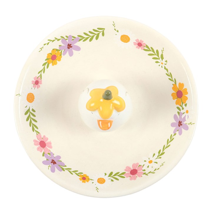 Ariel view of A small white ceramic trinket dish with a pastel wildflower border and a 3D duck figure in a yellow flower hat in the center, on a white background