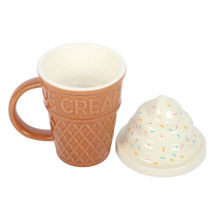 Ceramic mug shaped like a brown waffle ice cream cone with 'ICE CREAM' embossed on the rim, topped with a white swirled soft-serve lid with pastel sprinkles taken off and placed on the side.