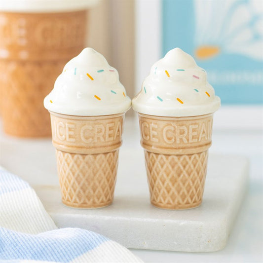 Two ceramic salt and pepper shakers shaped like ice cream cones with white soft-serve swirls and colourful sprinkles