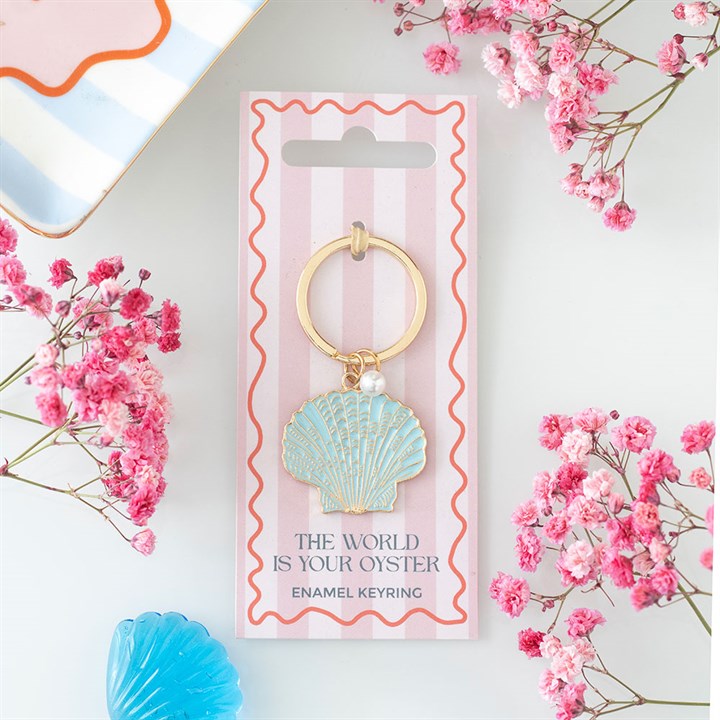 Mint green enamel clam shell keyring with a tiny faux pearl charm, mounted on a pink and white striped gift card reading 'The World is Your Oyster Enamel Keyring'.