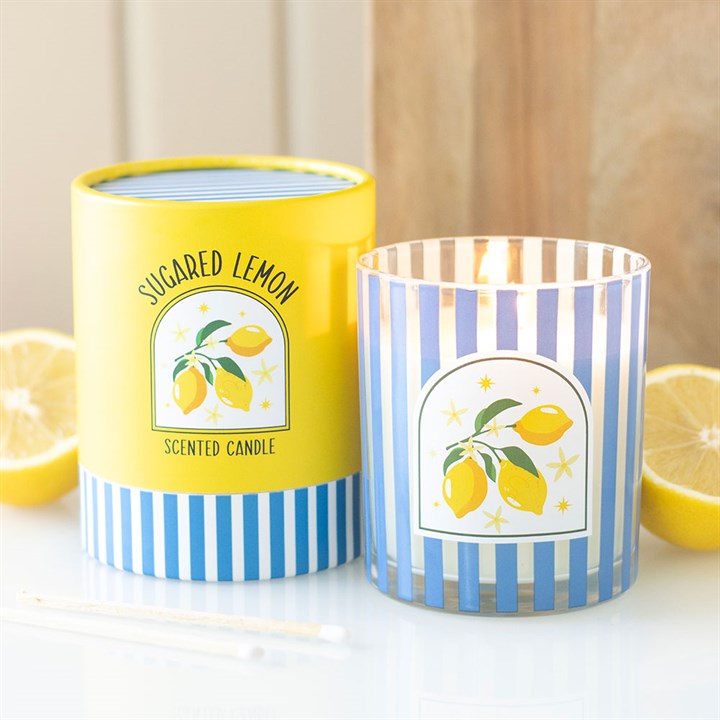 Blue and white vertical striped glass candle with a lemon illustration, sitting next to a matching yellow and blue striped gift tube.