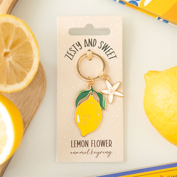 Gold-tone enamel keyring featuring a bright yellow lemon charm and a small white five-petal flower charm.