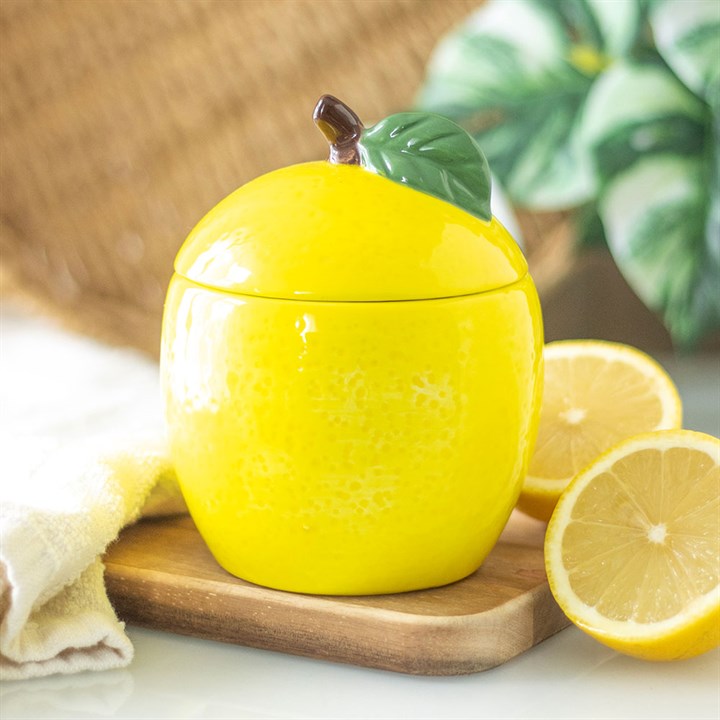 Textured yellow ceramic candle jar shaped like a lemon with green leaf detail with lid on